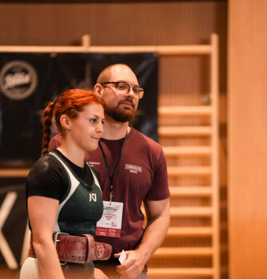 A powerlifting coach with his female athlete at the romandie championships a powerlifting coach working with female clients at a powerlifting competition