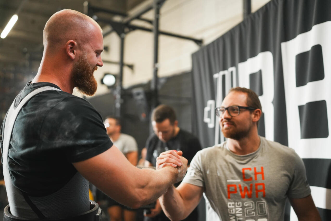 Athlete and Coach Julian Kohler Celebrating Powerlifting Success Powerlifting coach and athlete shaking hands after a successful lift, symbolizing trust, progress, and results in strength training and competitive powerlifting.
